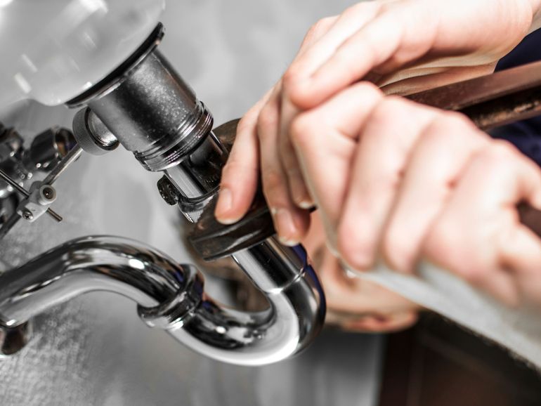 a plumber is working on a pipe with a wrench