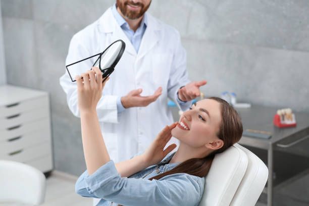 Young woman admiring her new dental crowns in Fairfax, VA at Magnolia Dental, with a smiling dentist