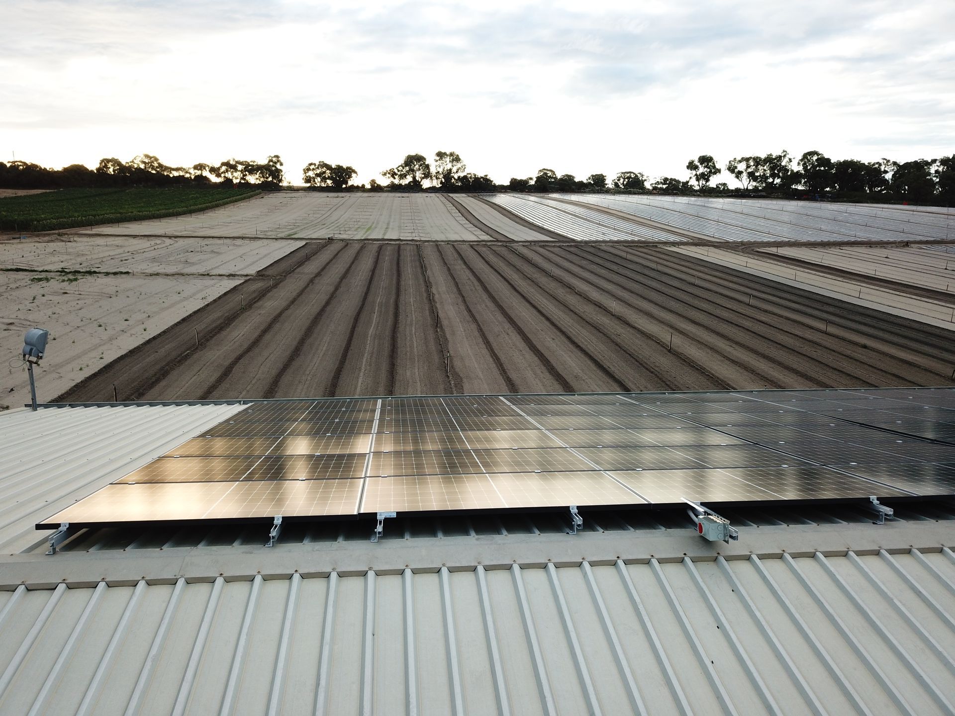 A roof with solar panels on it and a field in the background