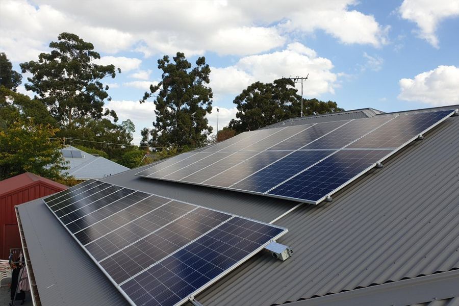 There are many solar panels on the roof of a house.