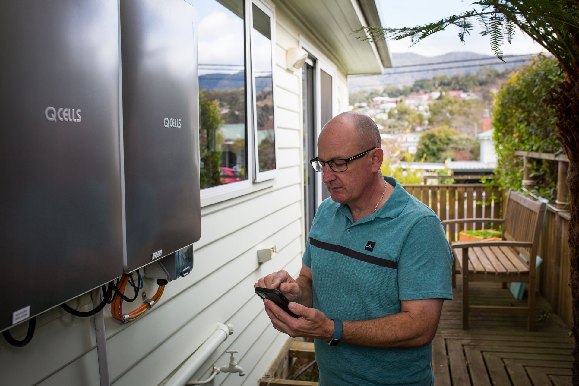 A man is standing outside of a house looking at his cell phone.