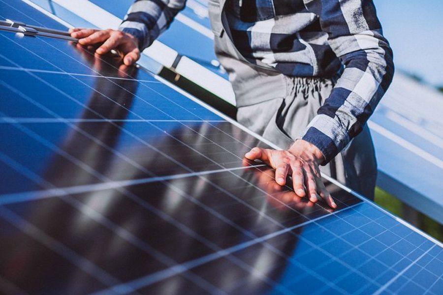 A man is working on a solar panel with a wrench.