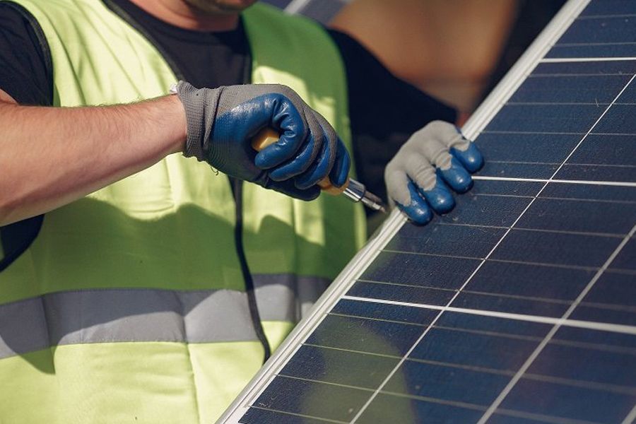 A man is working on a solar panel with a screwdriver.