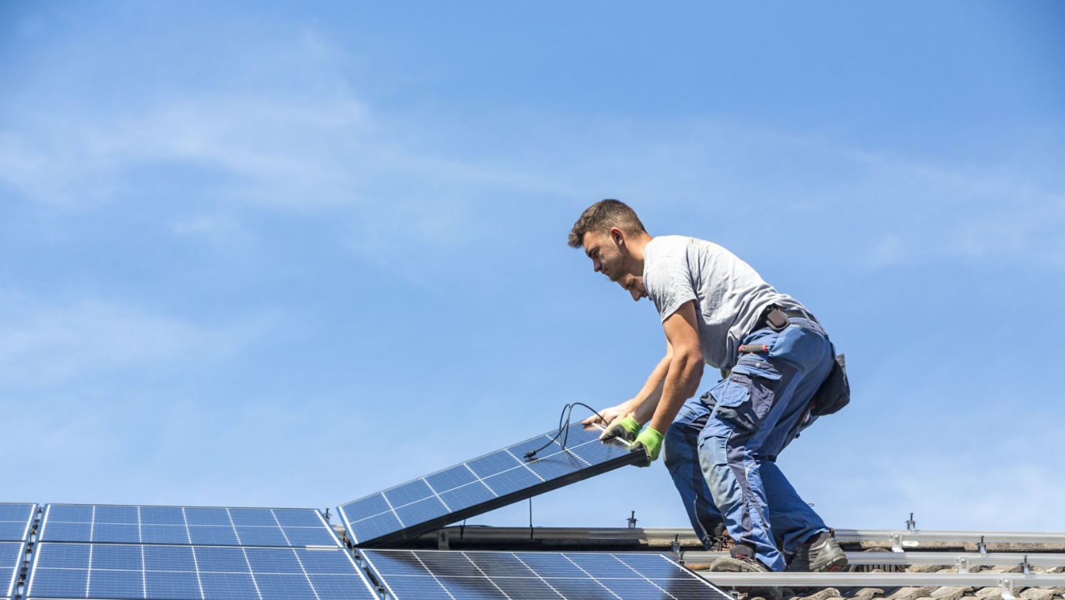 A man is installing solar panels on a roof.