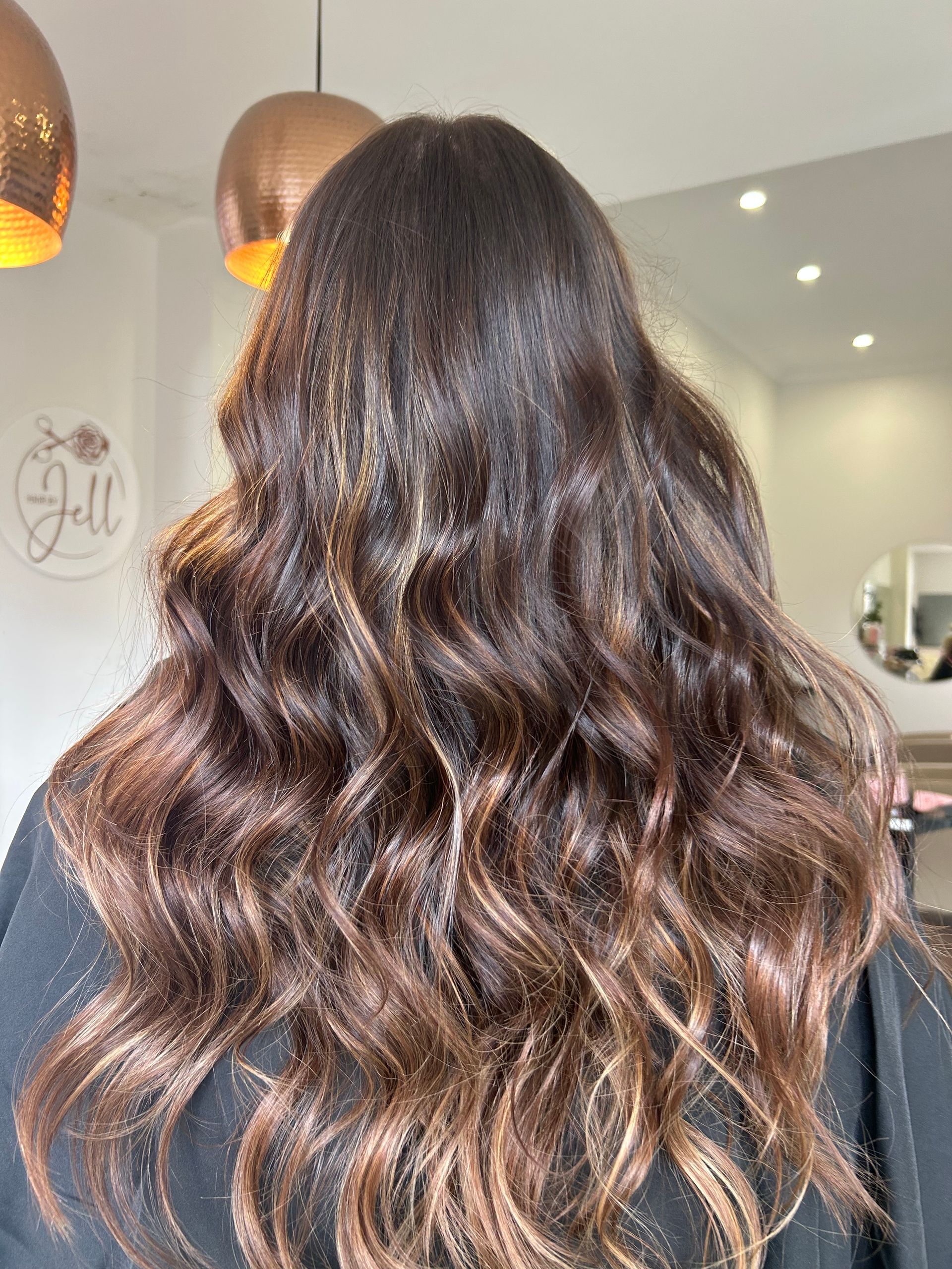 A Woman With Long Brown Hair is Sitting in a Salon — Hair By Jell In Cannonvale, QLD