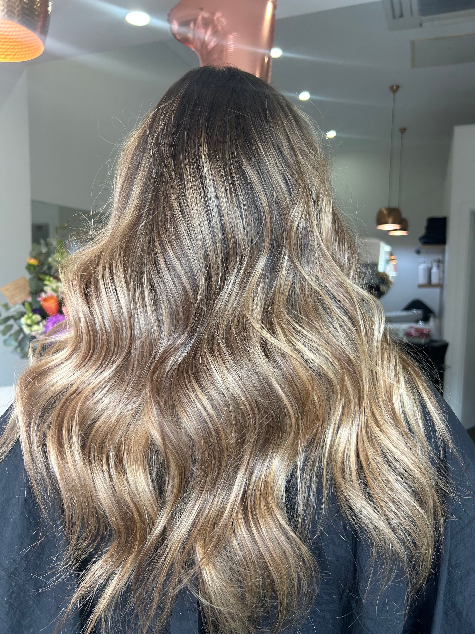 A Woman With Long Brown Hair is Sitting in a Salon — Hair By Jell In Cannonvale, QLD