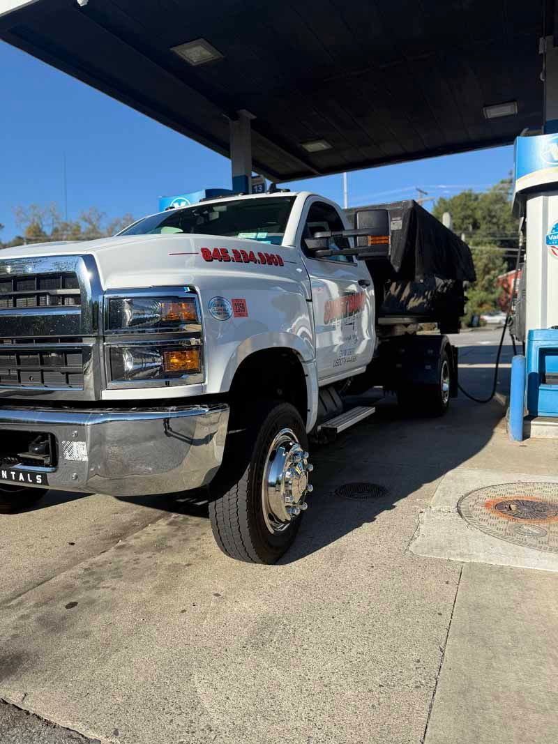 White dump truck parked at a gas station pump under a canopy