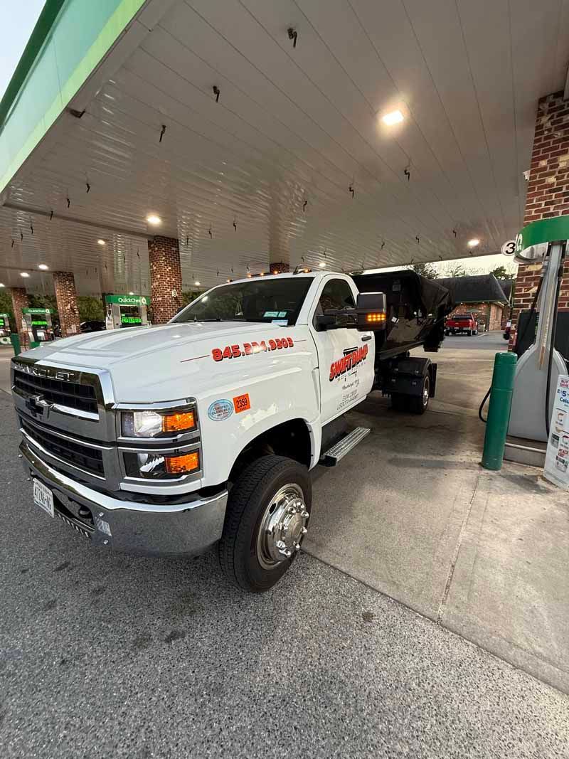 White Chevrolet pickup truck at a covered fuel station, parked by the pump.