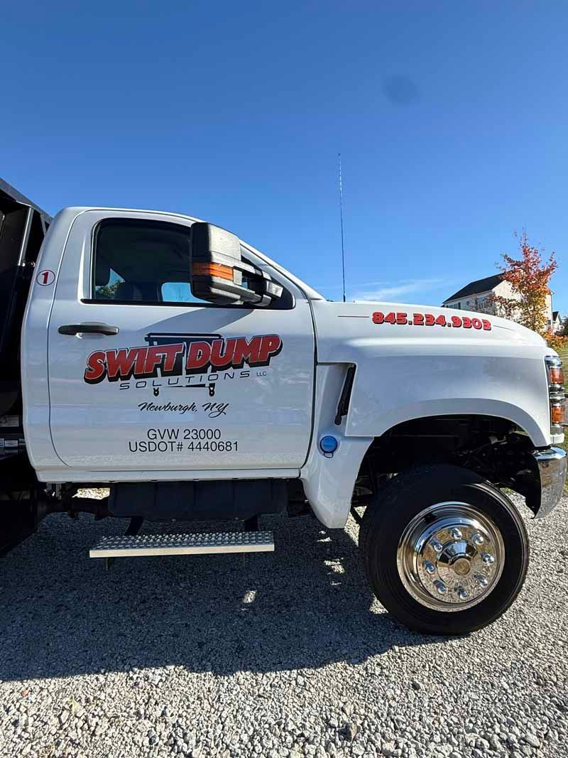 White lifted service truck with red logo parked on gravel under a clear blue sky