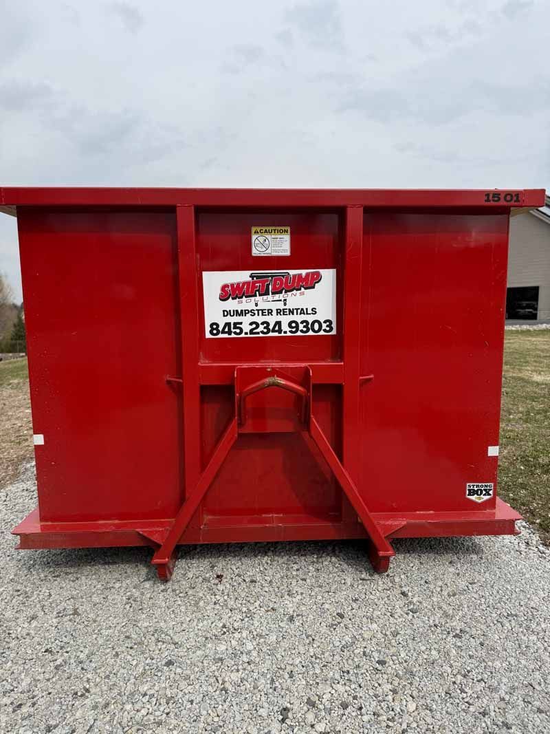 Red metal dumpster on gravel with a company sign on the front.