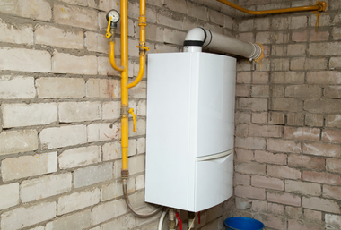 White wall-mounted boiler with yellow gas pipes in a brick utility room