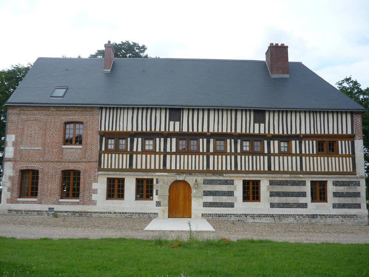 Bâtiment à ossature bois de deux étages avec des accents de brique et de pierre, un toit gris foncé et une porte en bois.