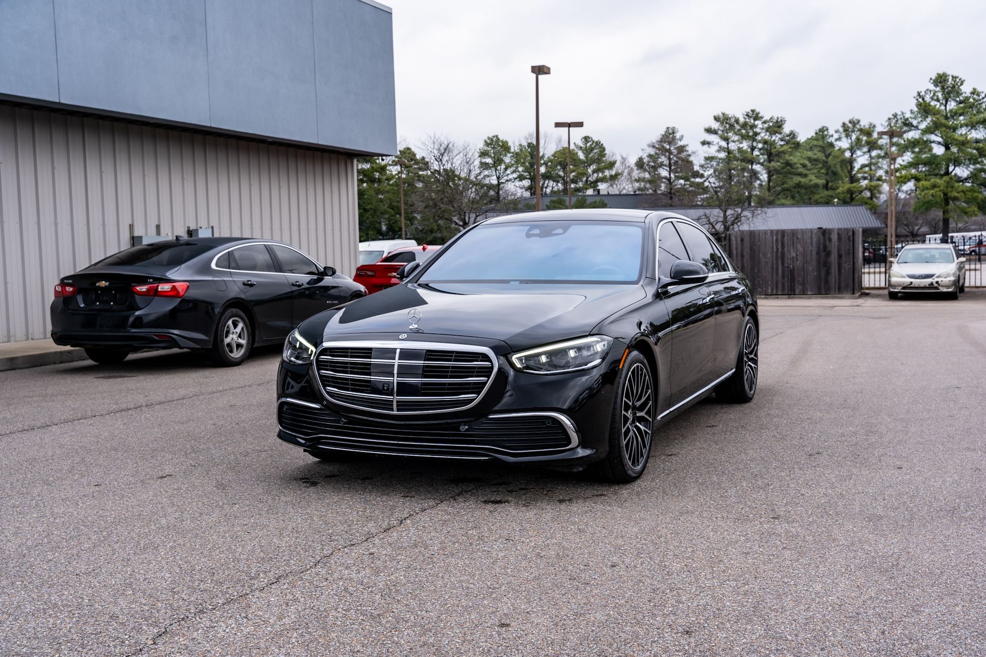 Black Mercedes-Benz sedan parked in front of a building on an overcast day.