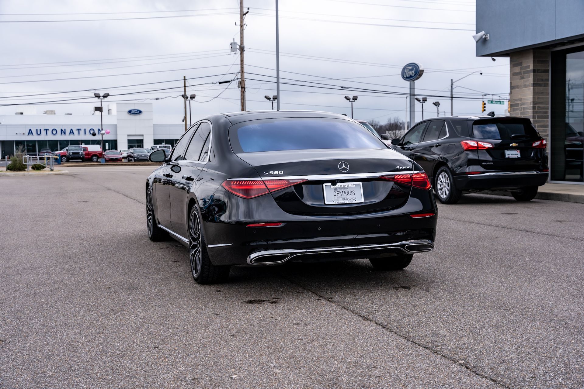 Black sedan parked in front of an AutoNation dealership on a cloudy day.