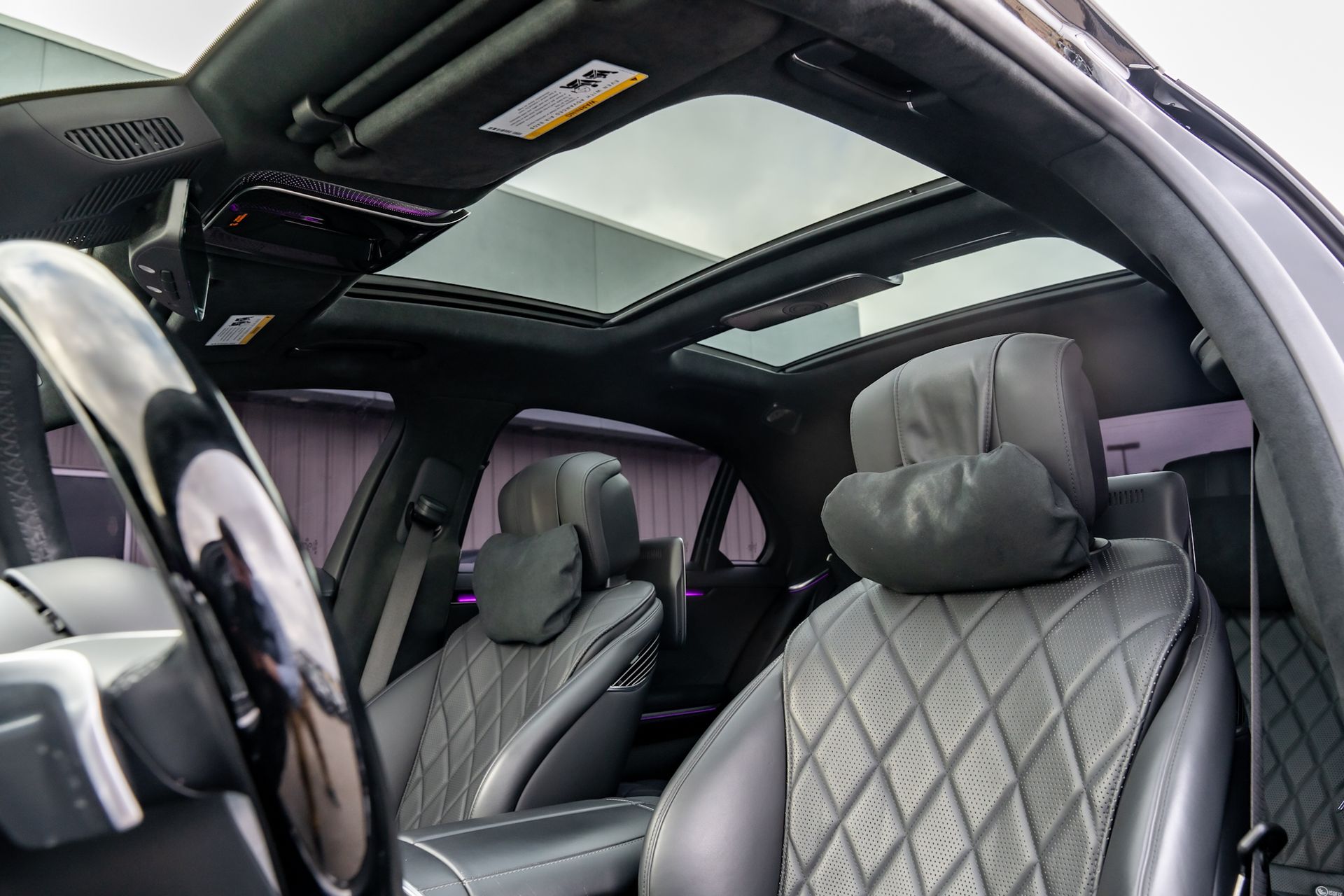 Interior of a black luxury car with leather seats, a sunroof, and a steering wheel.