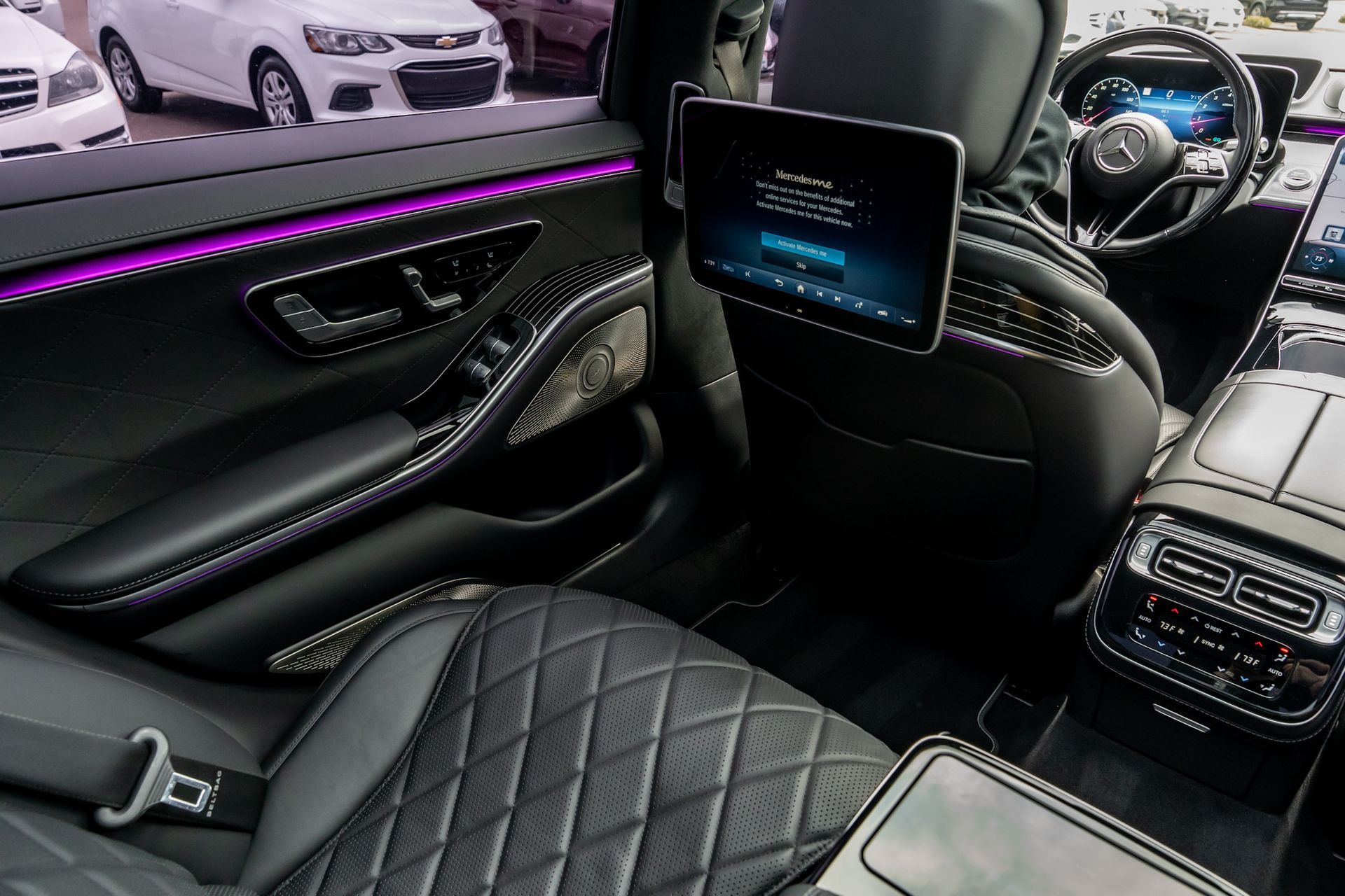 Luxury car interior with black leather seats, rear entertainment screen, and ambient lighting.
