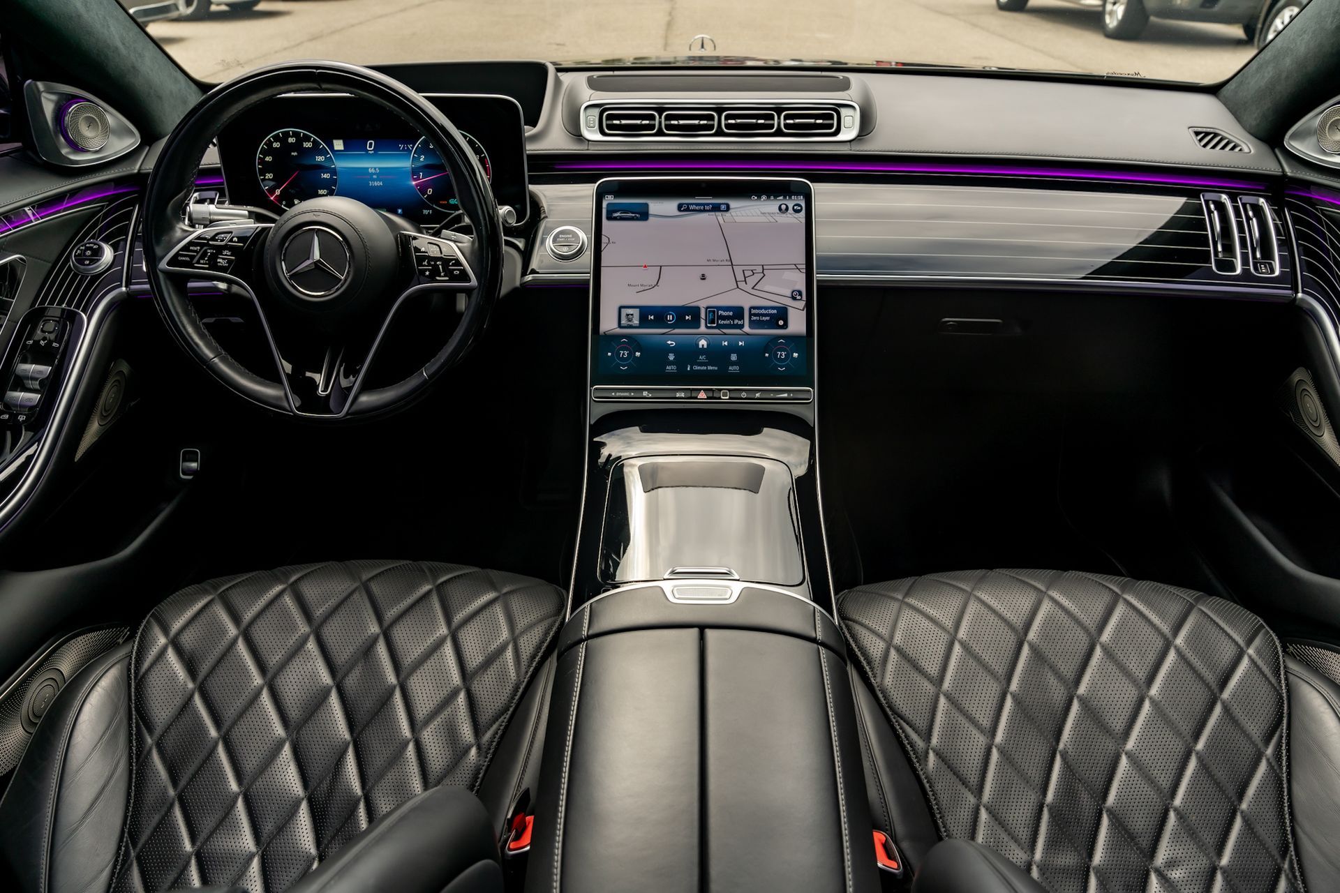 Mercedes-Benz S-Class interior with diamond-stitched black leather seats, large touchscreen, and digital instrument panel.