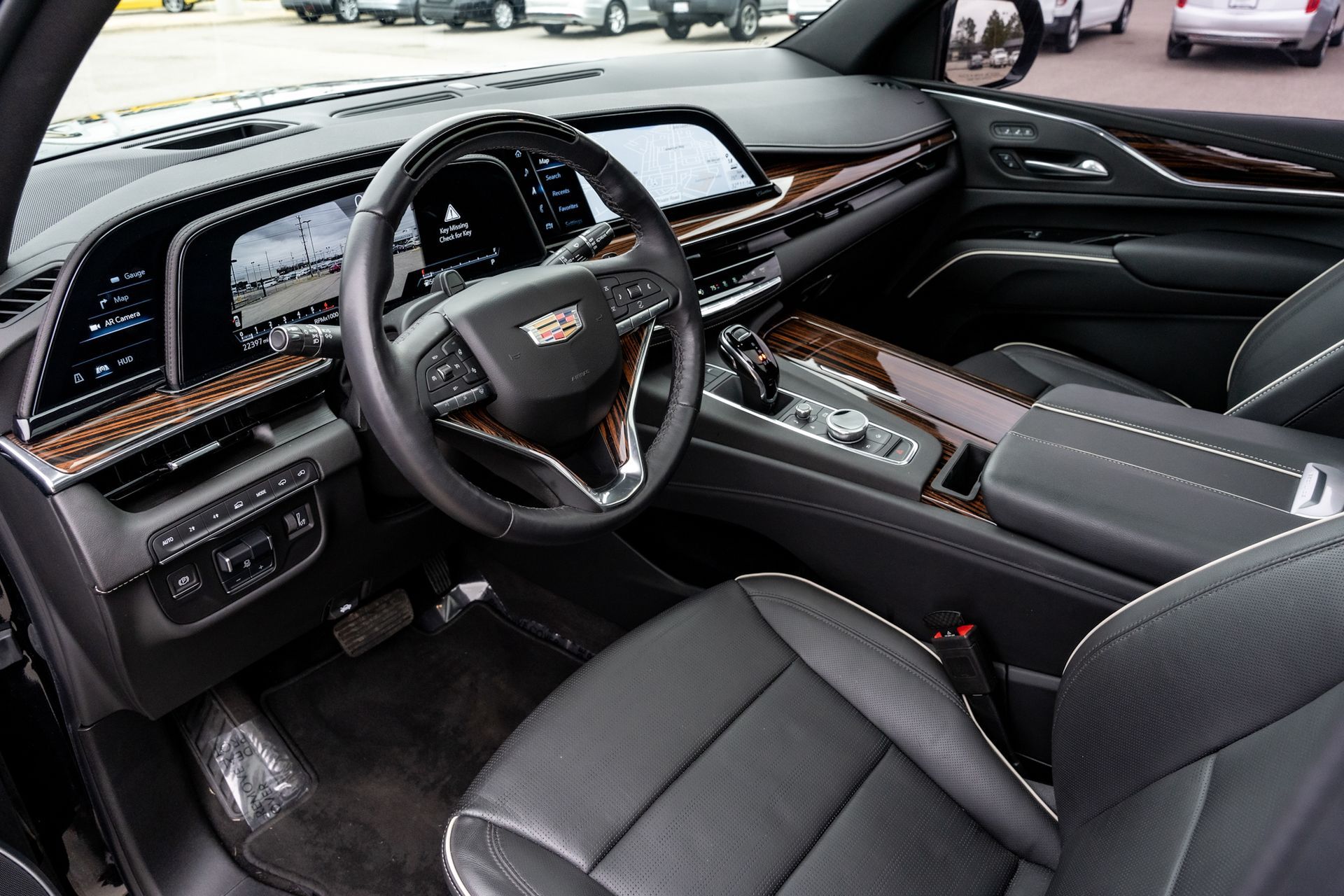 Cadillac Escalade interior: black leather seats, wood trim, digital displays, steering wheel.