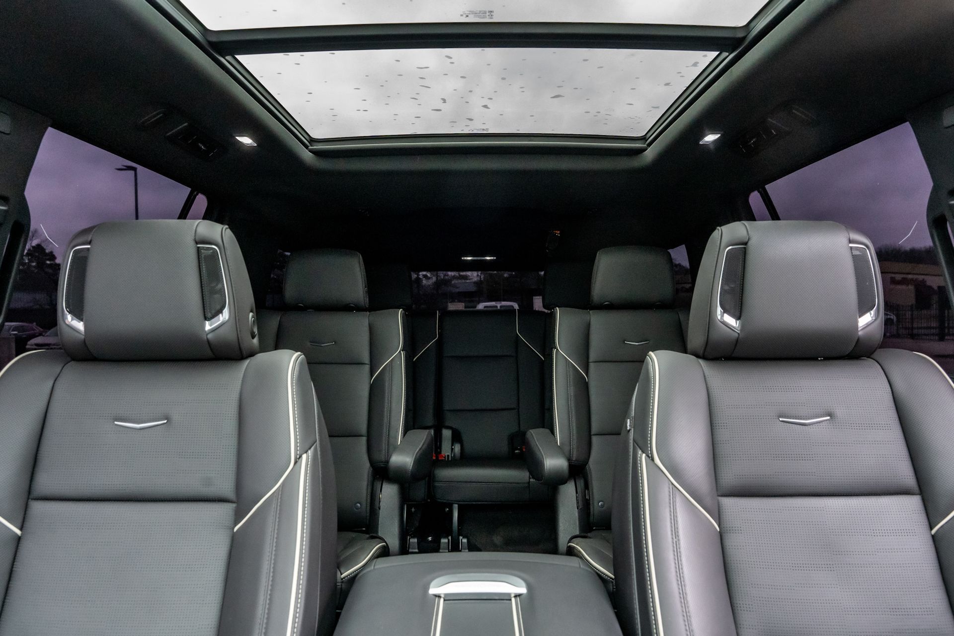 Interior of a luxury SUV, black leather seats, panoramic sunroof, with overhead lighting.