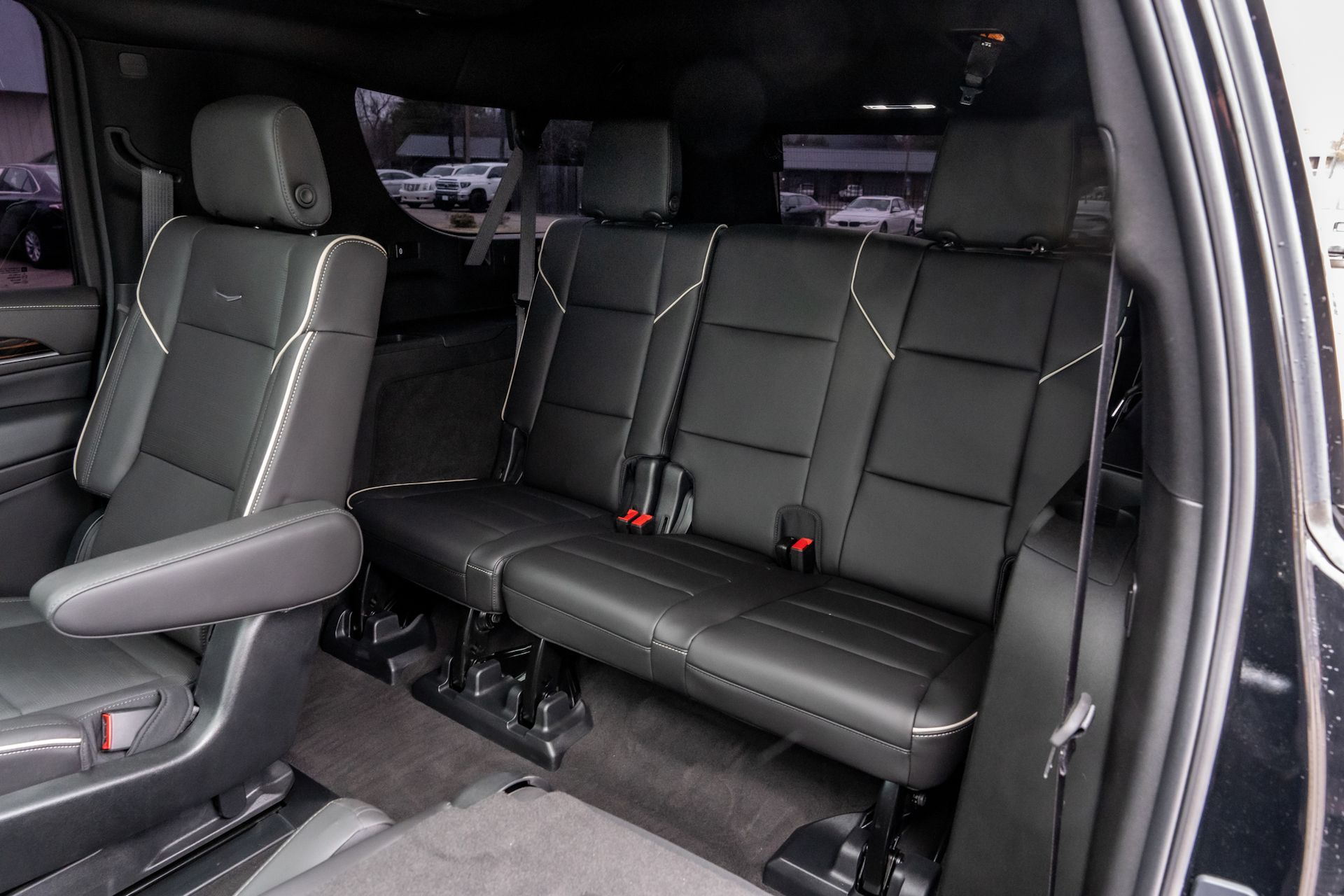 Black leather interior of a vehicle with two rows of seats.