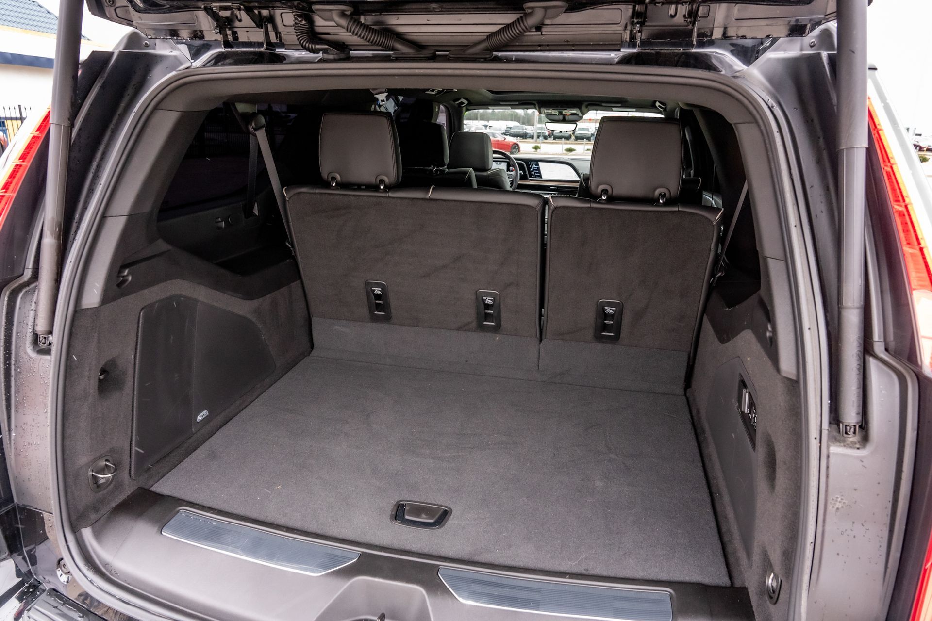 Rear cargo area of a dark SUV with the seats folded down, showing a gray carpeted floor.
