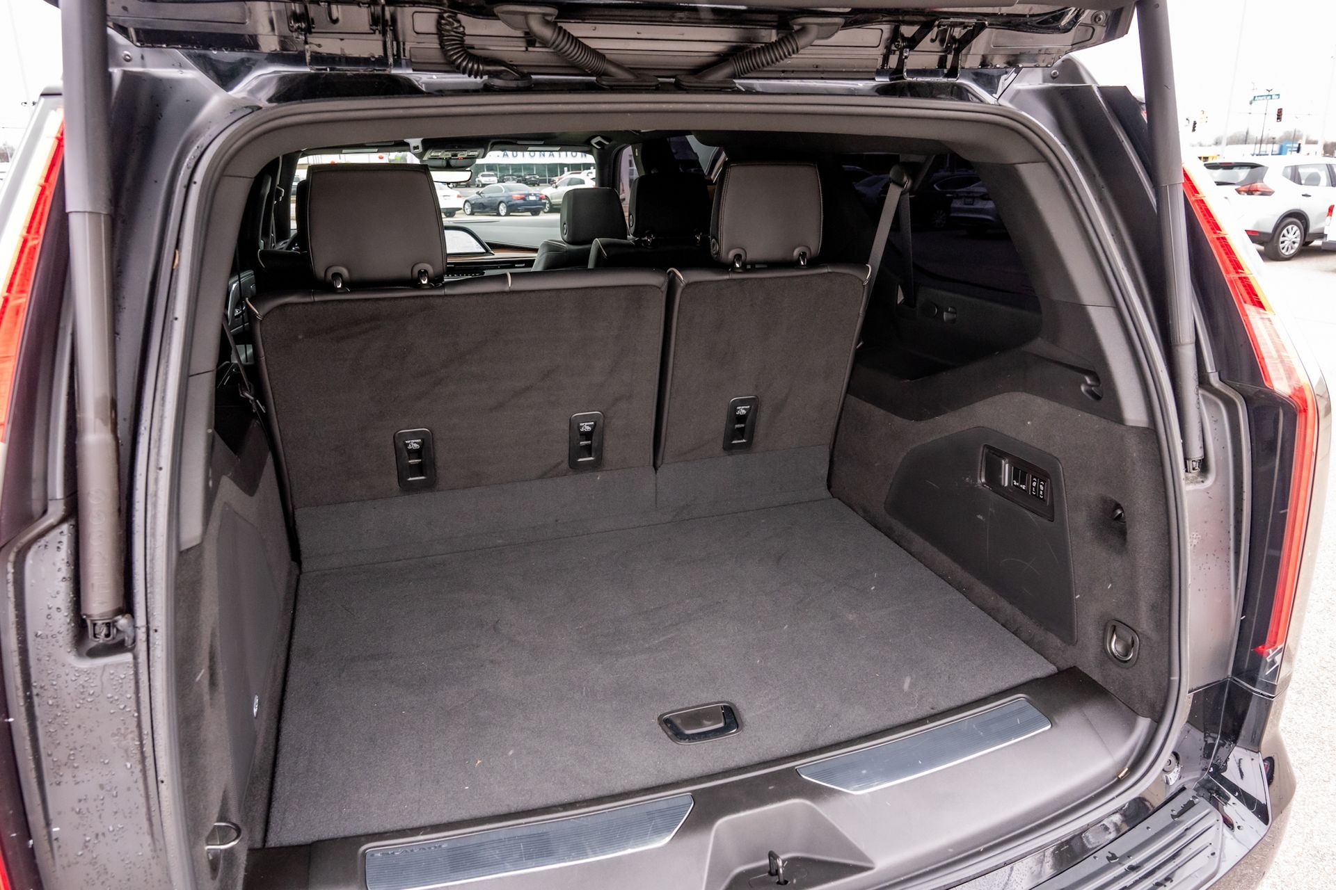 Black SUV cargo area with folded seats, gray carpet, and open hatch.