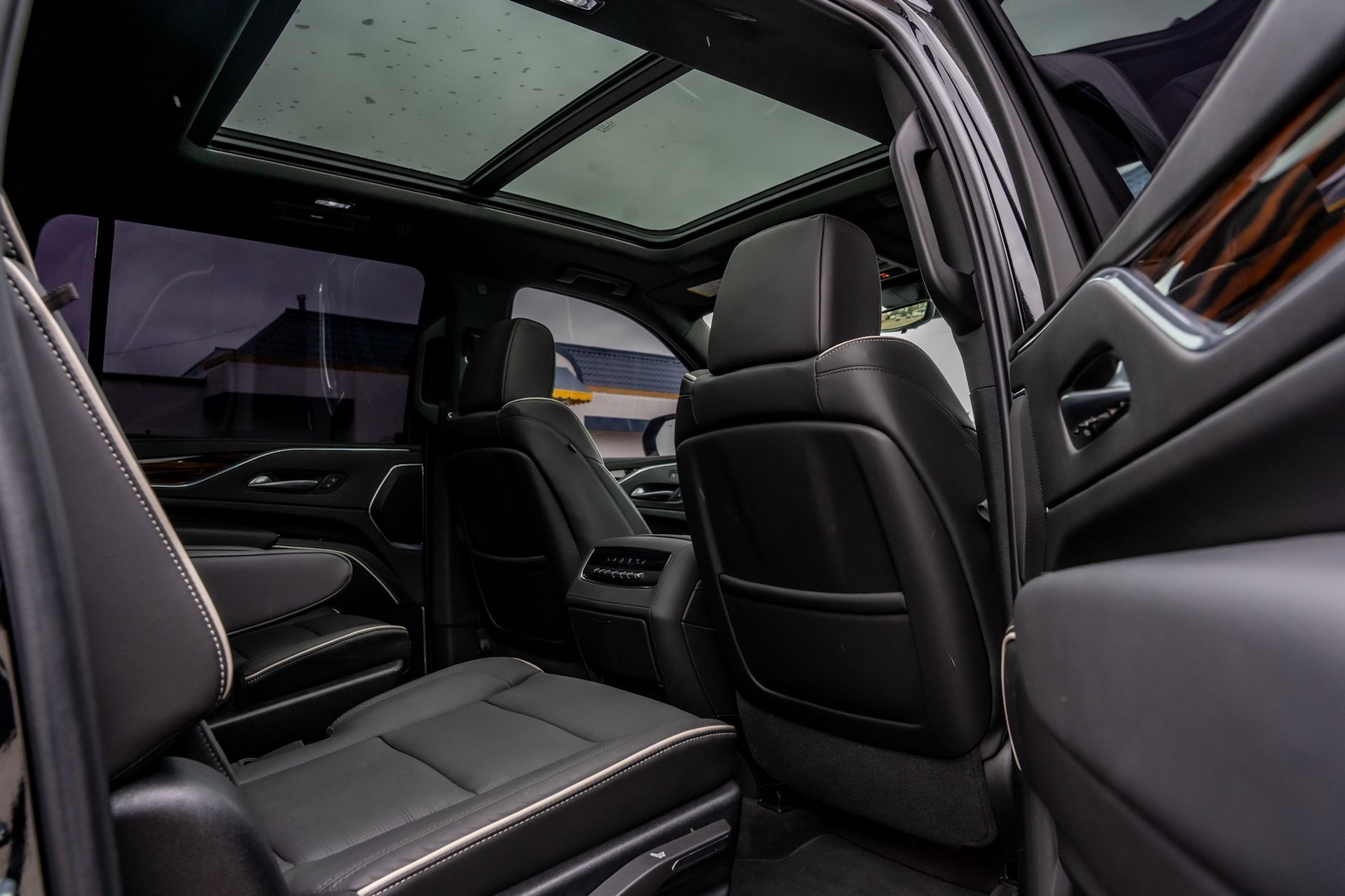 Interior of a black SUV with leather seats, panoramic sunroof, and wood trim accents.