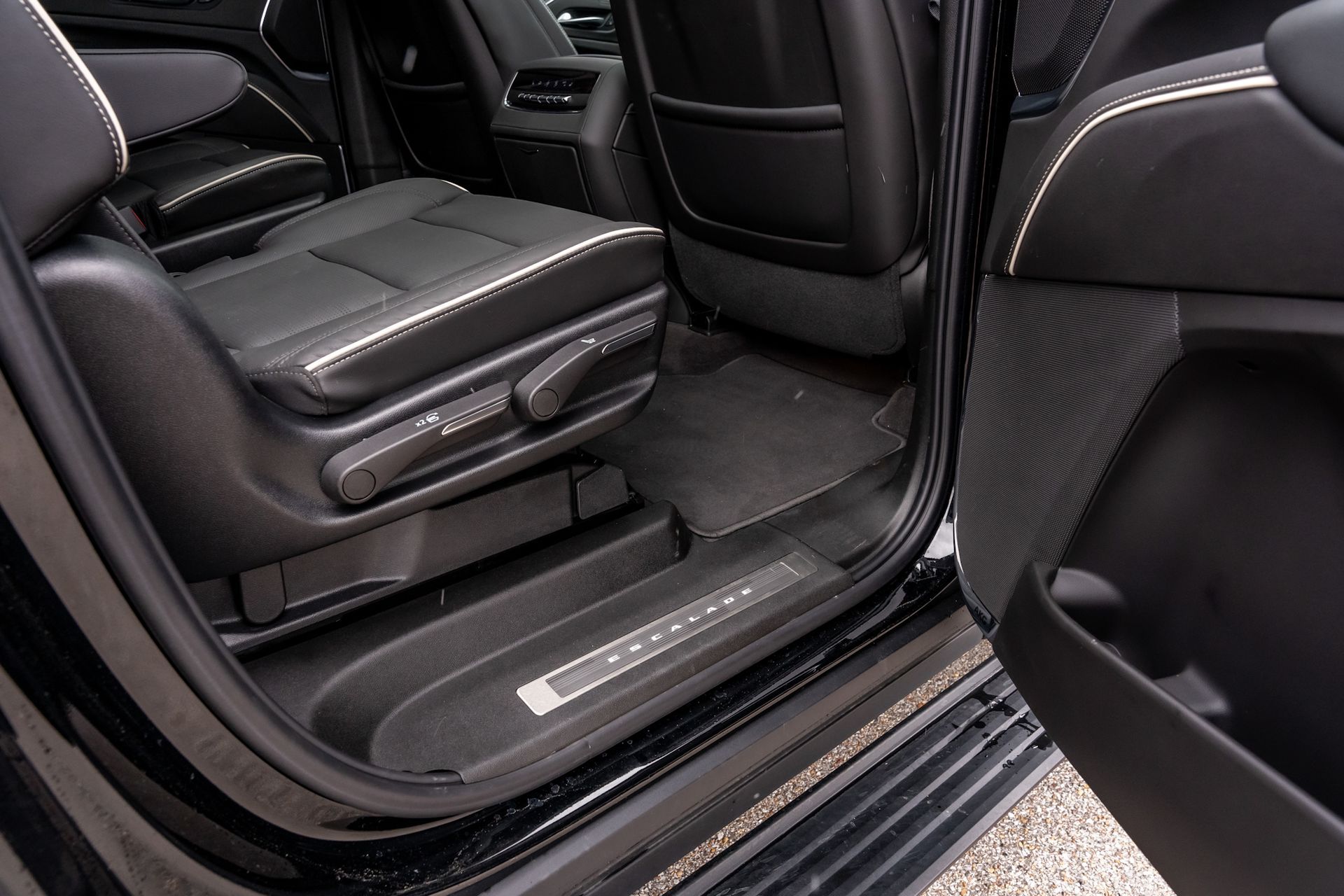 Black SUV interior with back seats, illuminated door sill, and black floor mat.