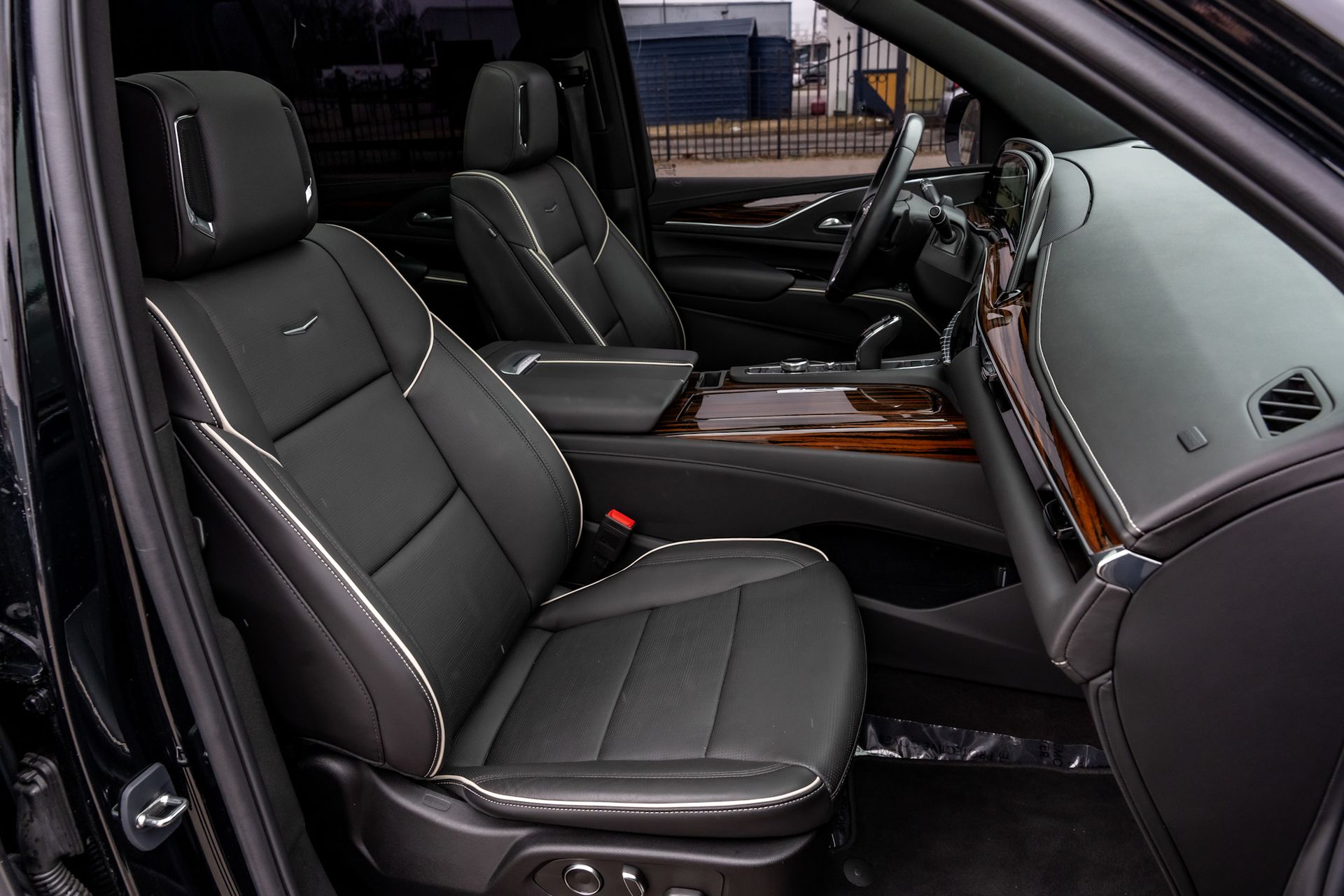Black leather car seats in a vehicle interior with wood trim and a steering wheel visible.