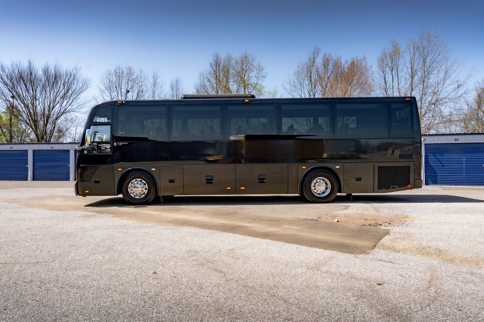 Black coach bus parked outside on a sunny day.