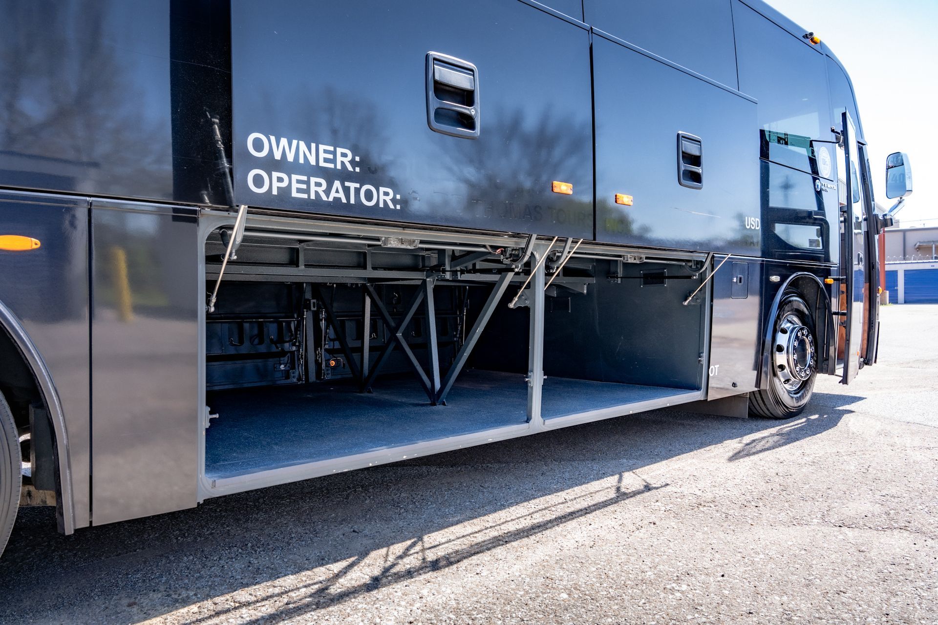 Black bus with open storage compartments. Exterior view.