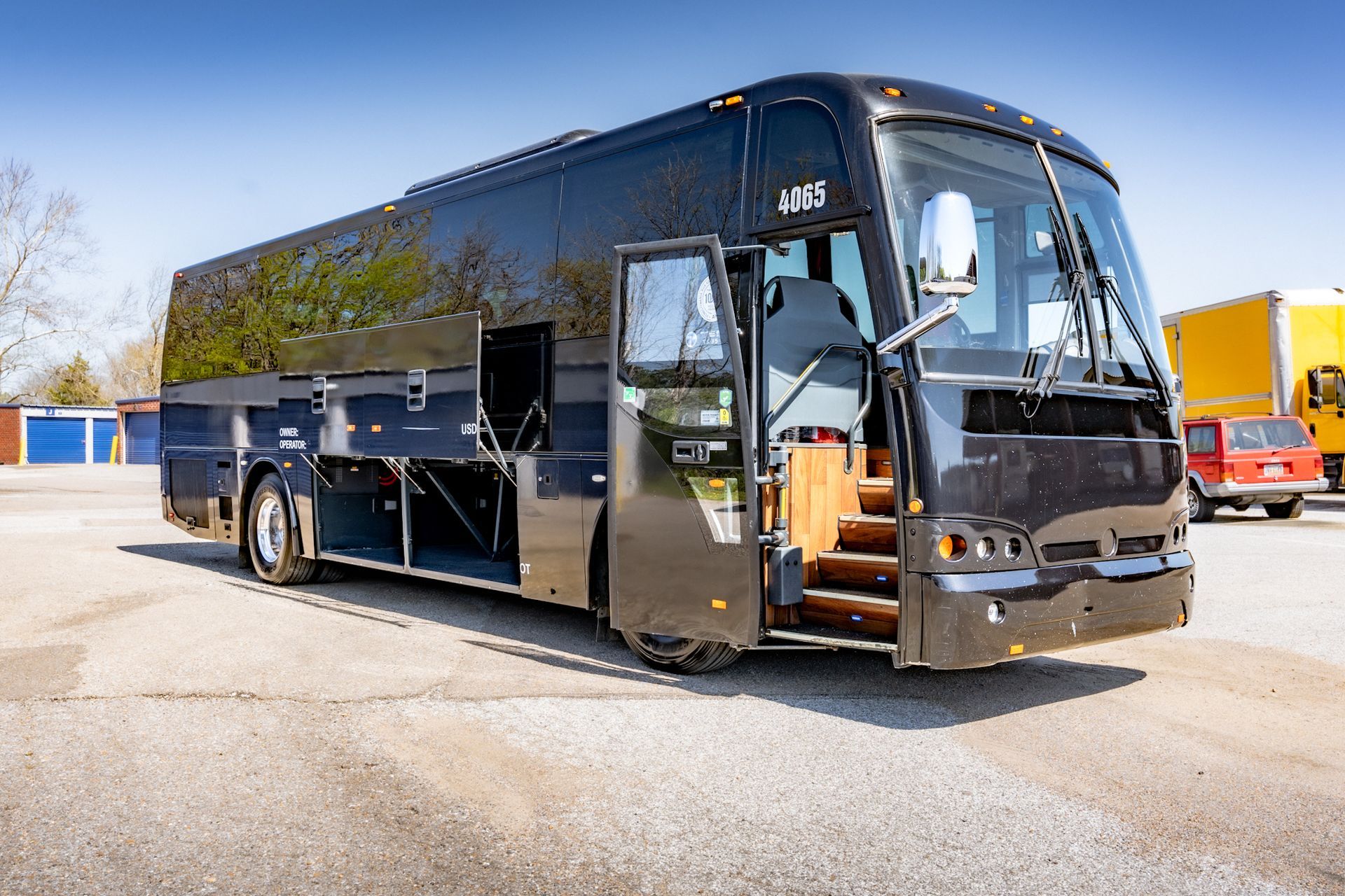 Black tour bus with open door parked outdoors.