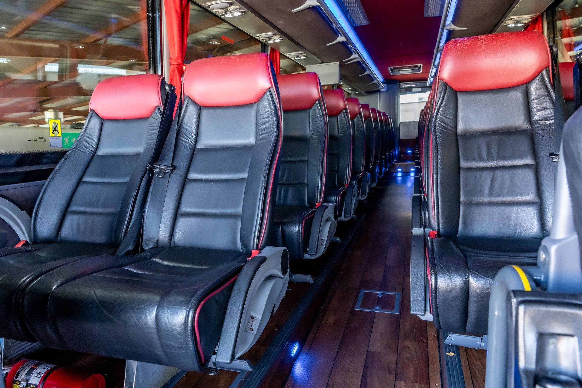 Interior of a bus showing black and red leather seats arranged in rows with a central aisle.
