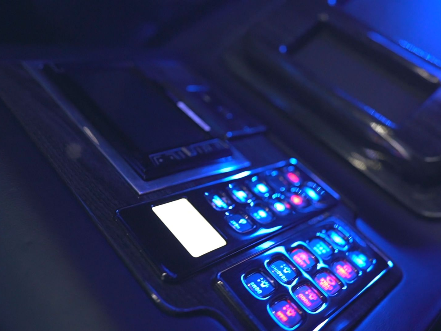 Control panel with glowing blue and red buttons and a bright white screen.