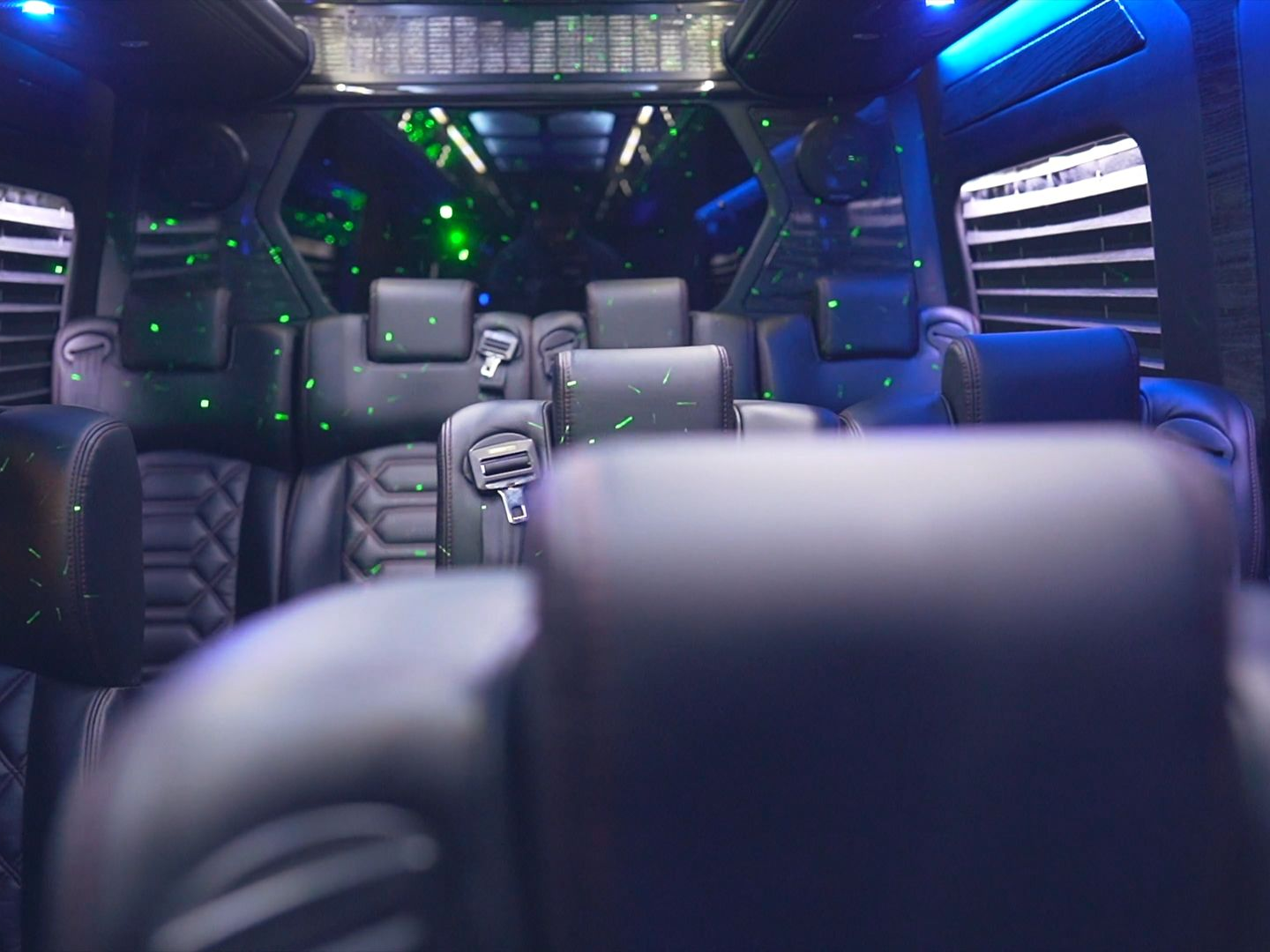 Interior of a luxury van with black leather seating and ambient lighting.
