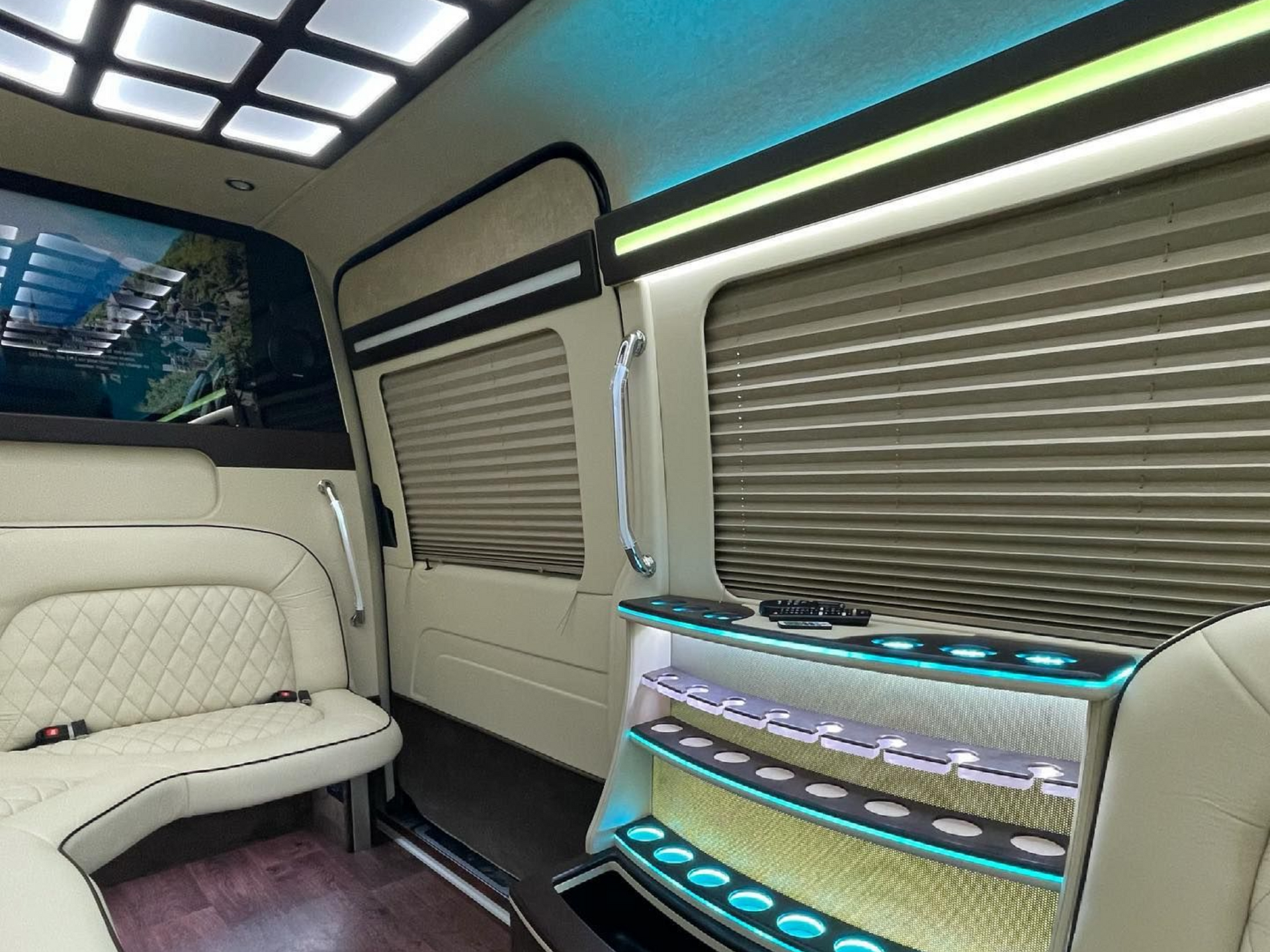 Interior of a luxury van with cream-colored seating, wood flooring, and LED lighting.