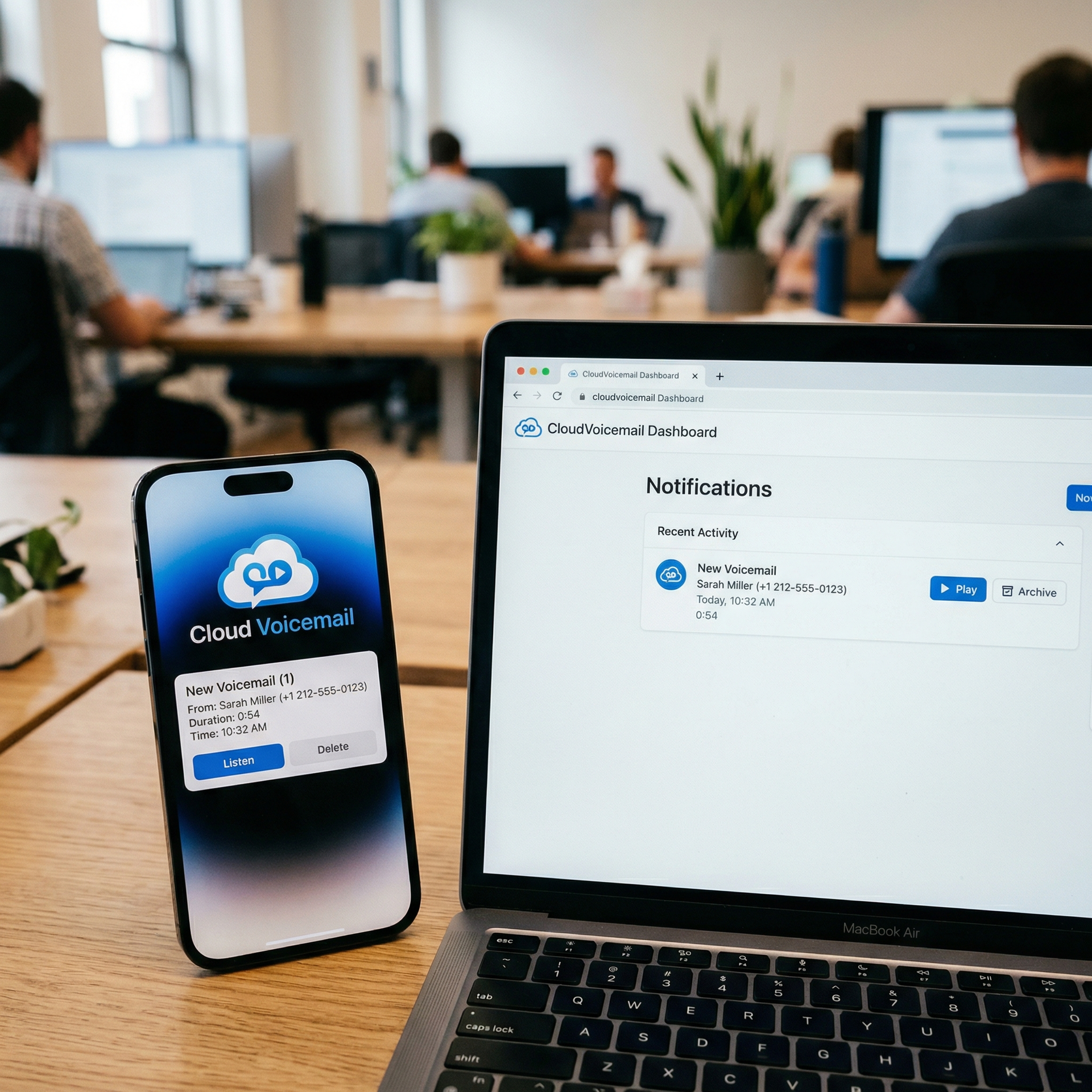A smartphone and laptop on a wooden desk in an office, displaying matching Cloud Voicemail app notifications.