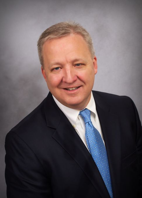 A man in a suit and tie is smiling for the camera