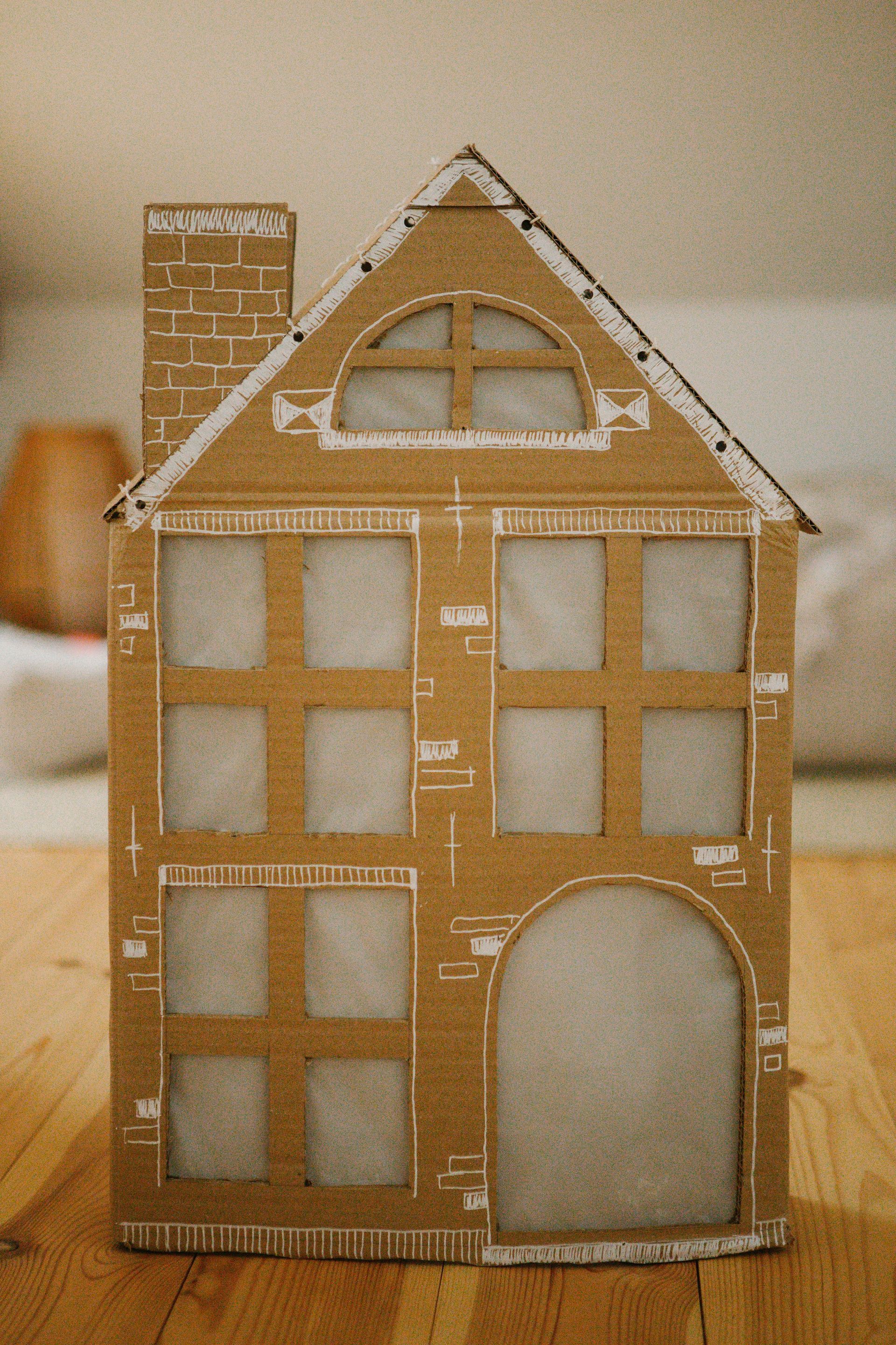 A cardboard house is sitting on a wooden table.