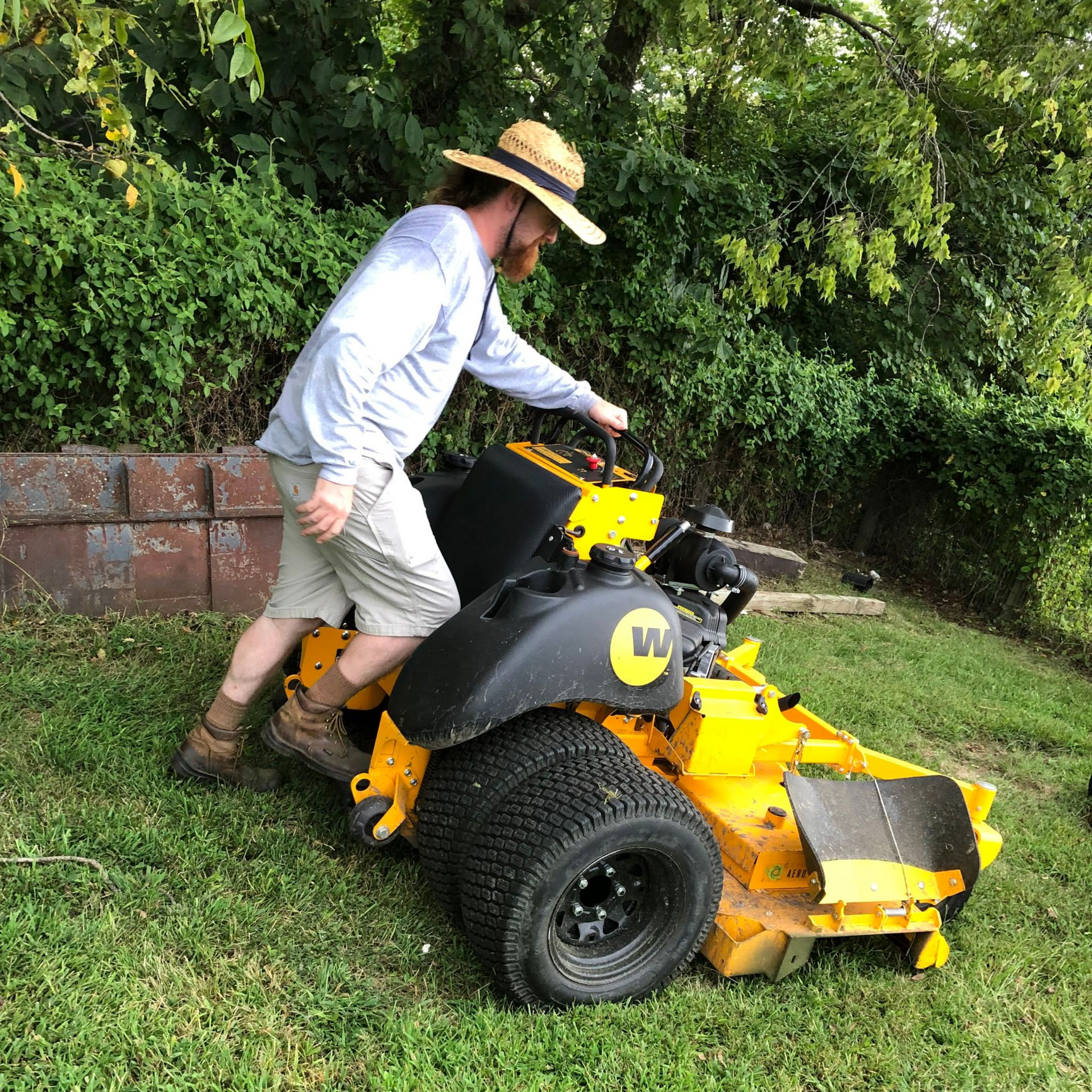 Quality lawn care in kansas city yellow lawn mower with man riding