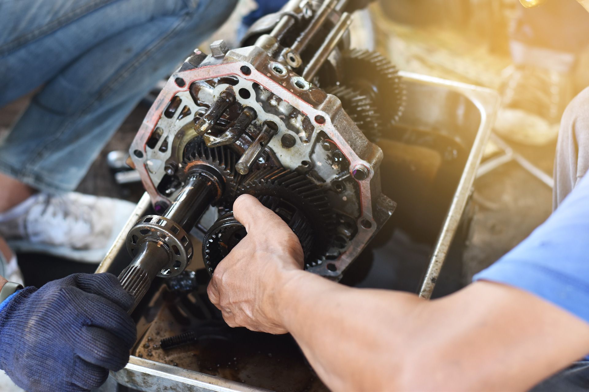 A man is working on a gearbox in a garage.
