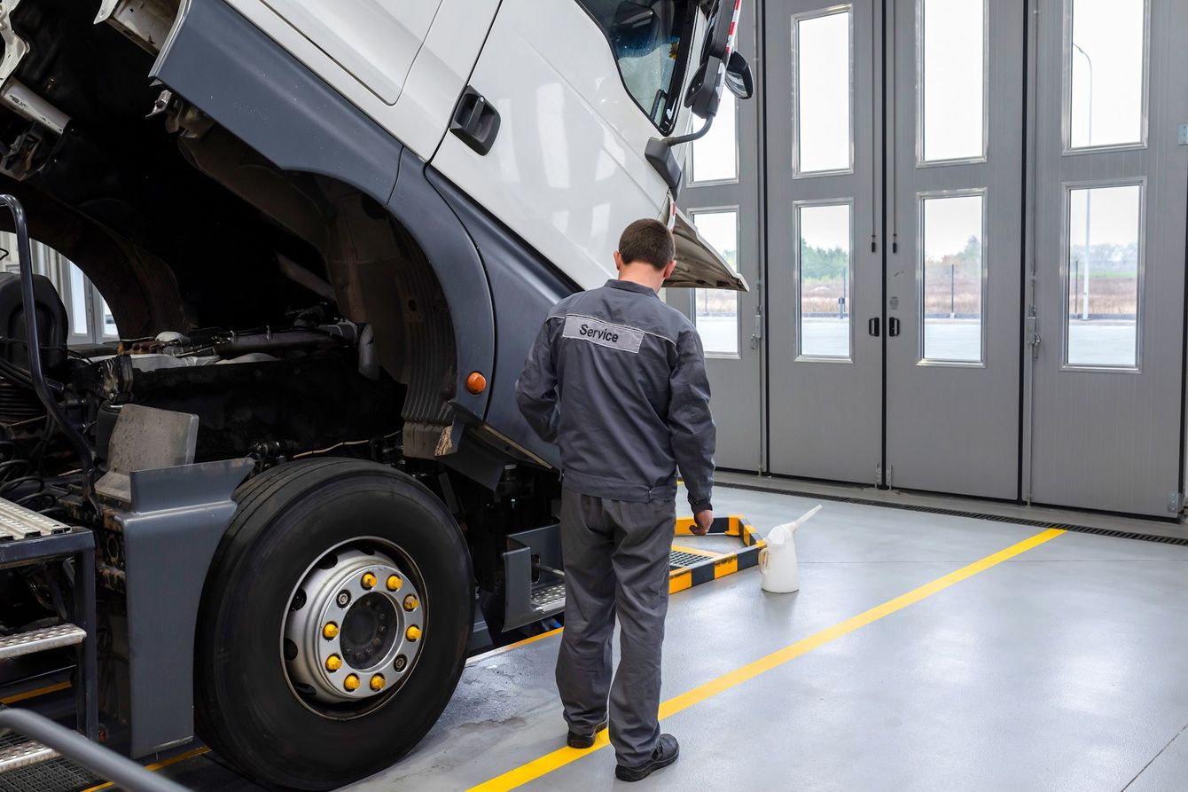 A man is working on a truck in a garage.