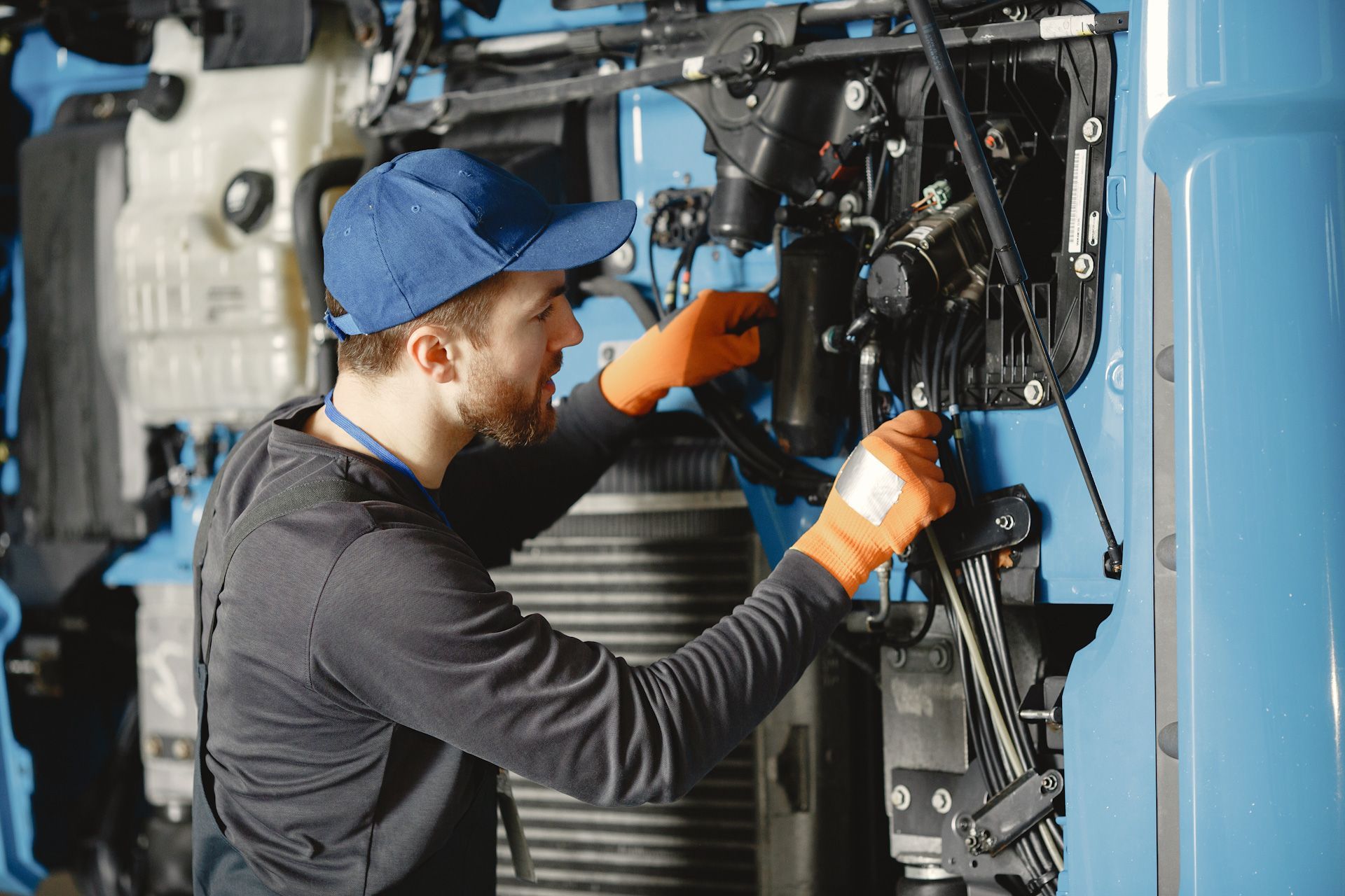 A man is working on the engine of a blue truck.
