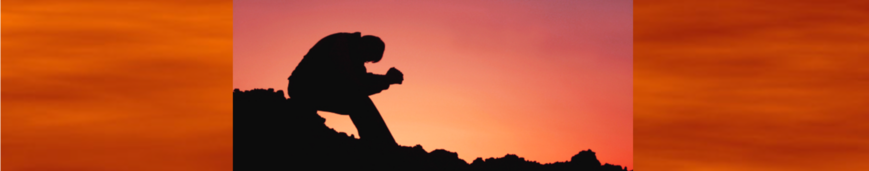 Silhouette of a person holding a camera at sunset against an orange sky