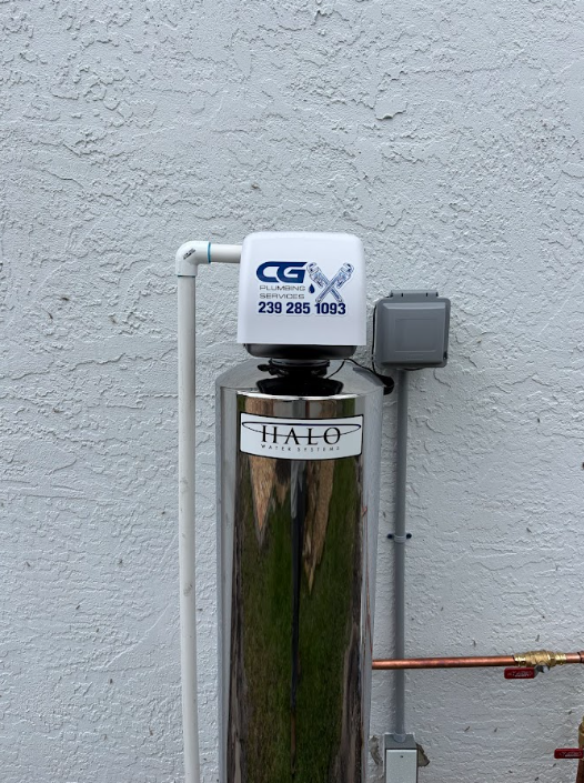 Outdoor utility equipment with a metal tank, white pipe box, and gray electrical box on a stucco wall