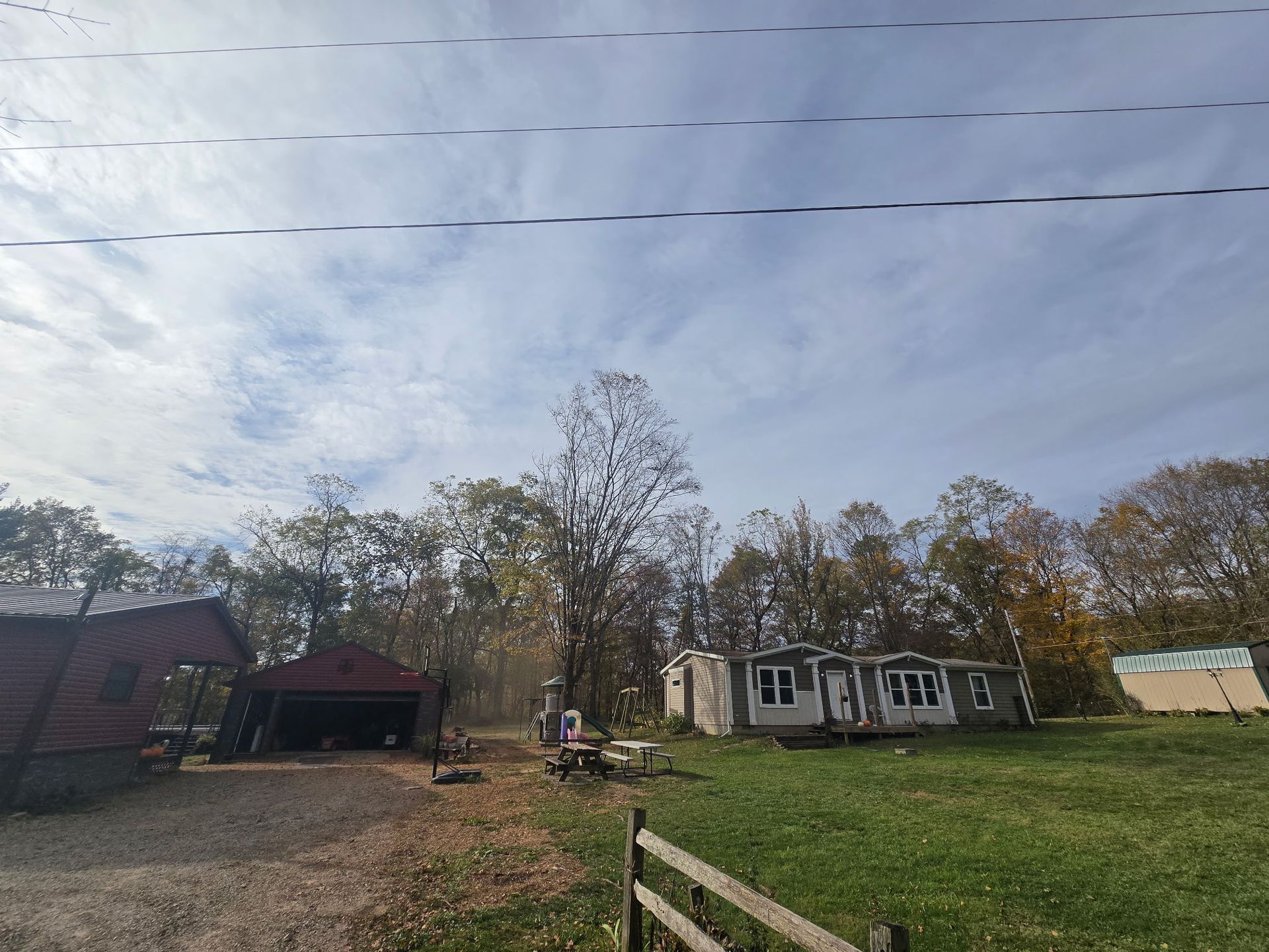 A rural scene with a house and shed under a cloudy sky.