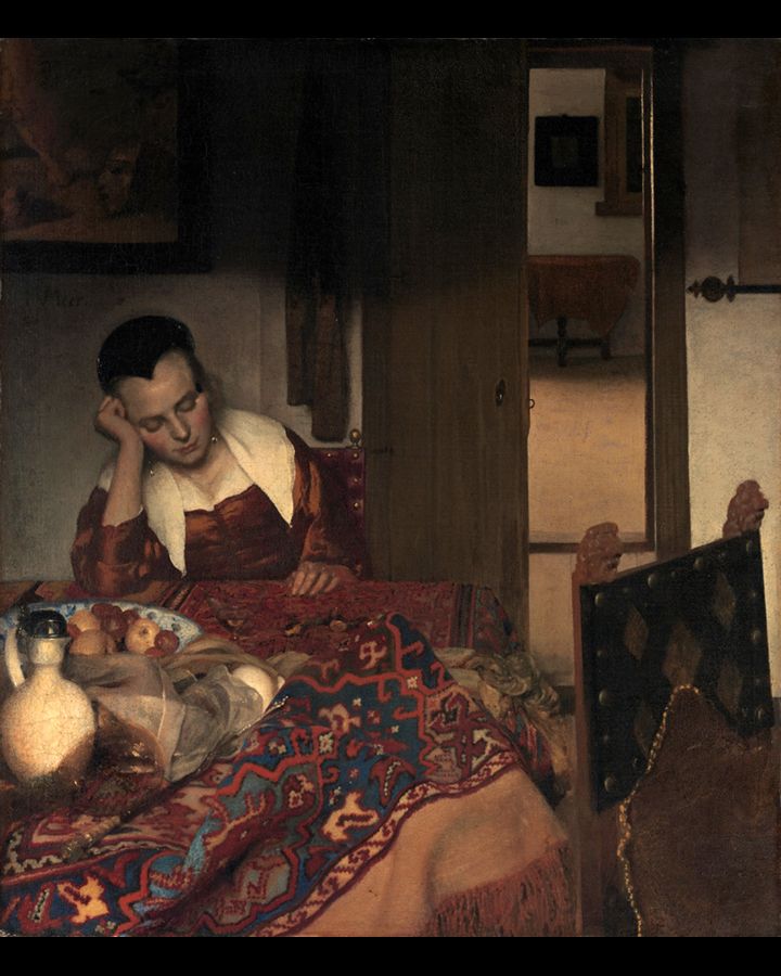 Vrouw die haar hoofd op haar hand laat rusten aan een tafel met fruit en een kan. Interieur met een open deur naar een andere kamer.