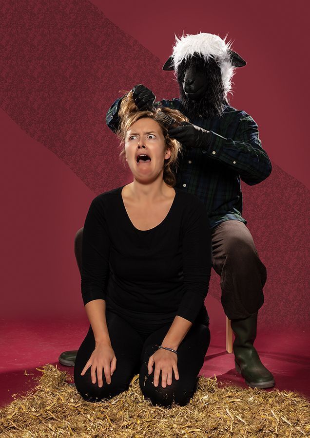 Een angstige  knielende vrouw, een schaap scheert haar. De scène speelt zich af op een hooiberg met een rode achtergrond.