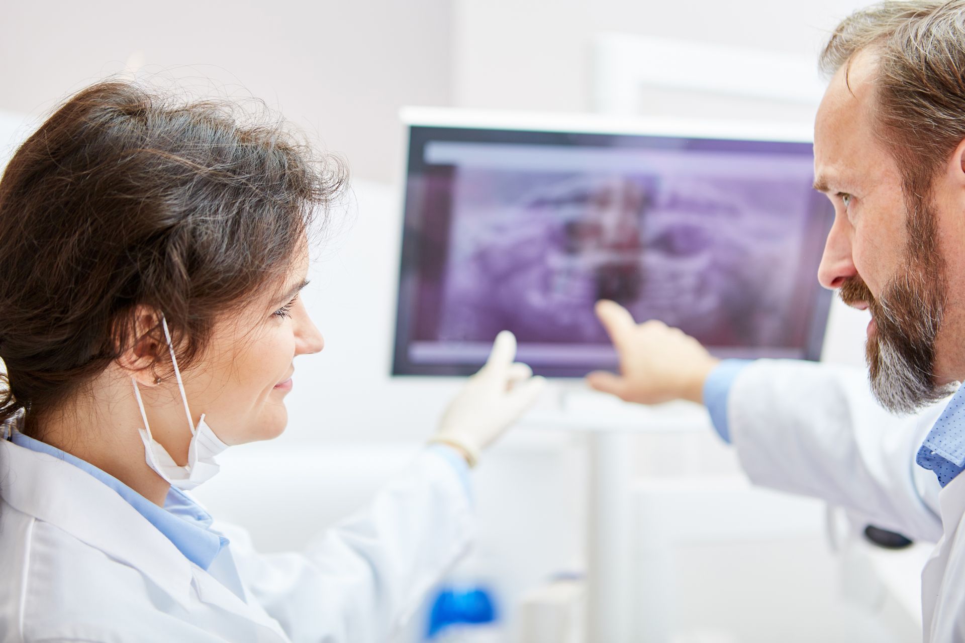 Doctors discussing an X-ray on a monitor in a bright clinic