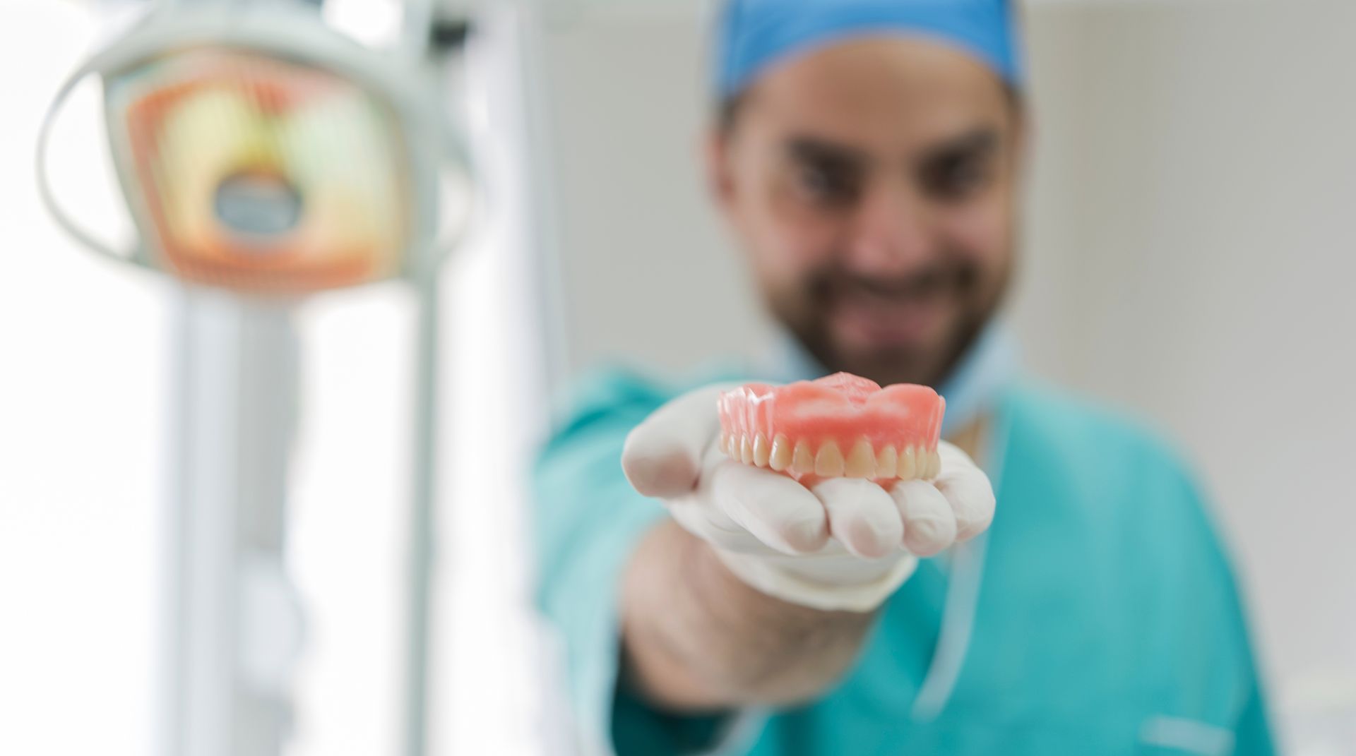 Dentist holding a set of dentures toward the camera in a clinic